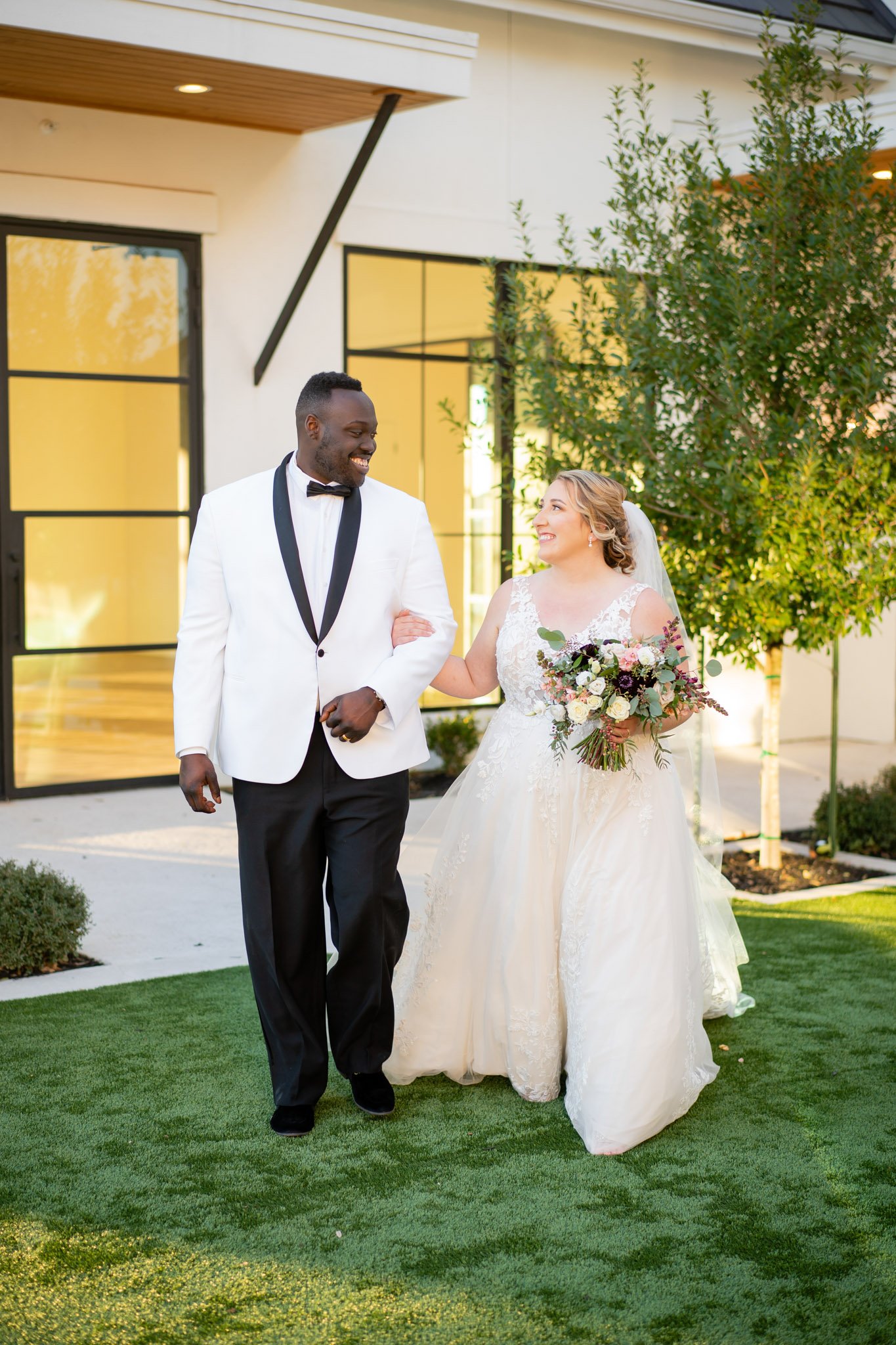 Interracial newlyweds smiling at each other walking arm in arm at The Arlo Texas The Amber Studio
