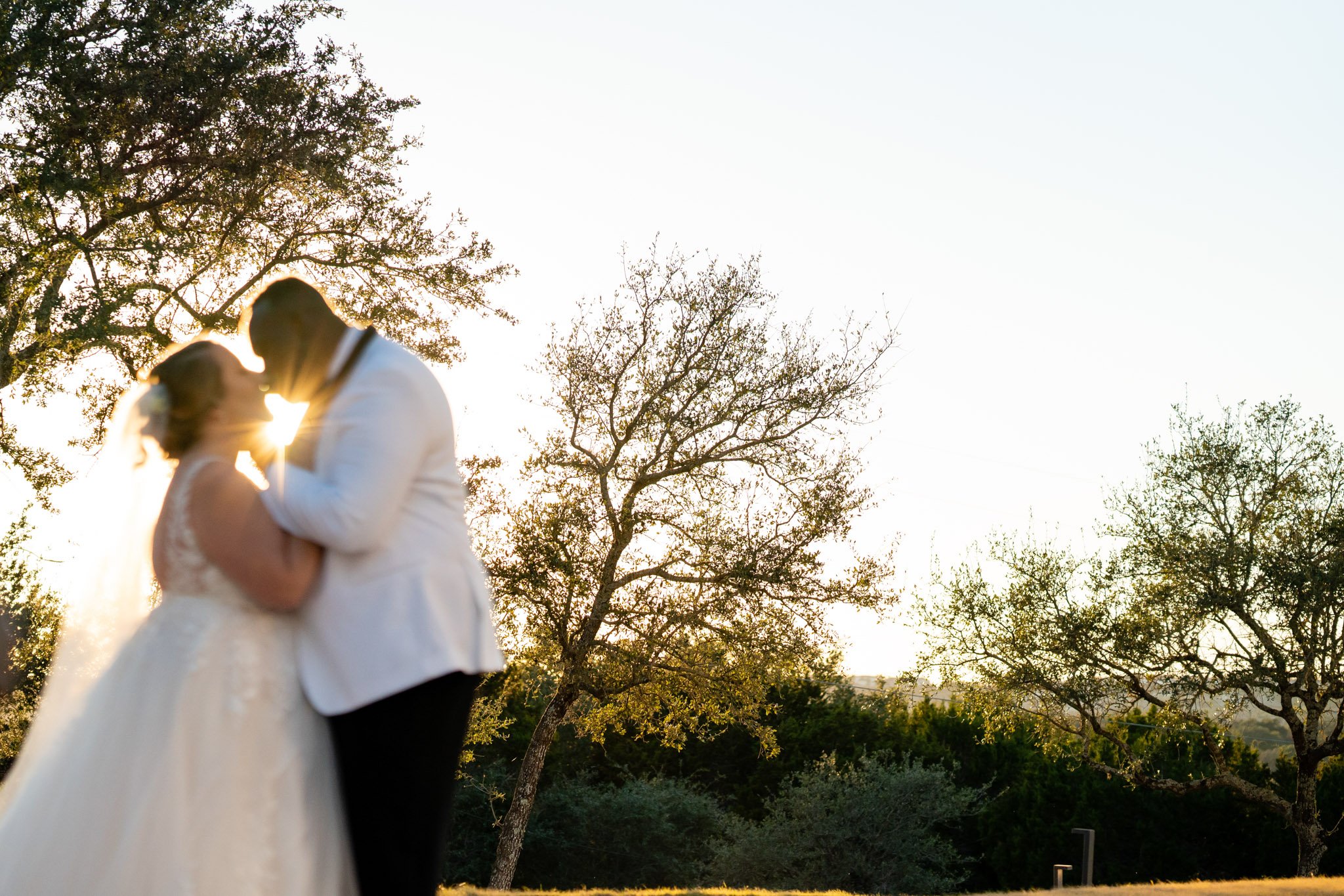 Newlyweds lean in to kiss before the setting sun outside in Austin Texas The Amber Studio