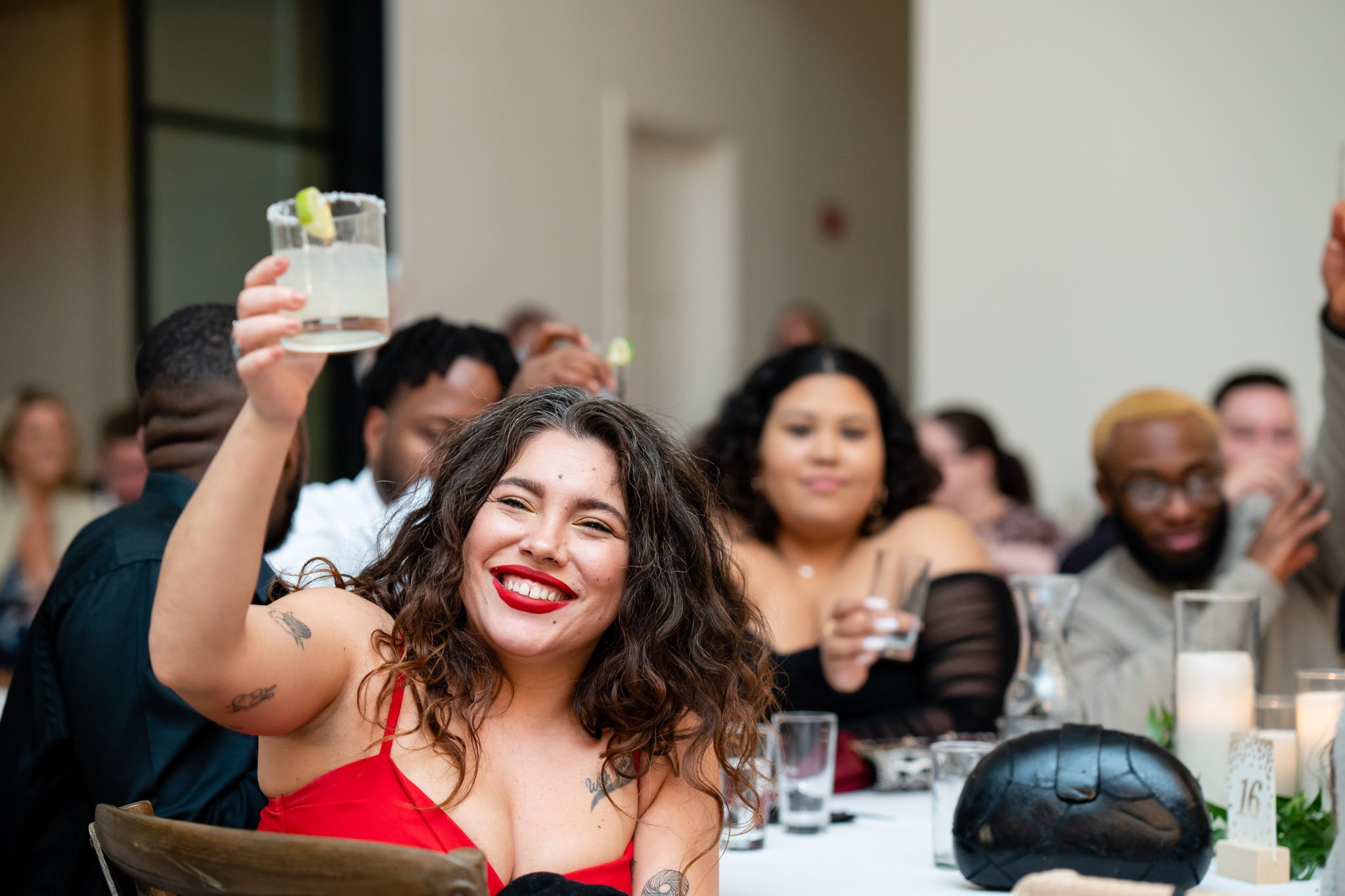 A wedding guest in a red dress raises a glass at the Arlo in Texas The Amber Studio