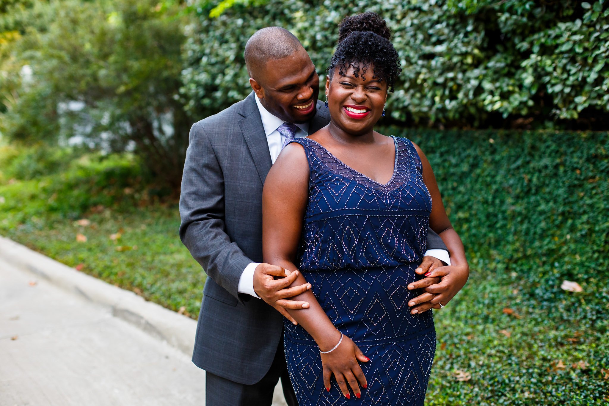 A woman in a blue gown being embraced by her partner from behind outside in DFW The Amber Studio