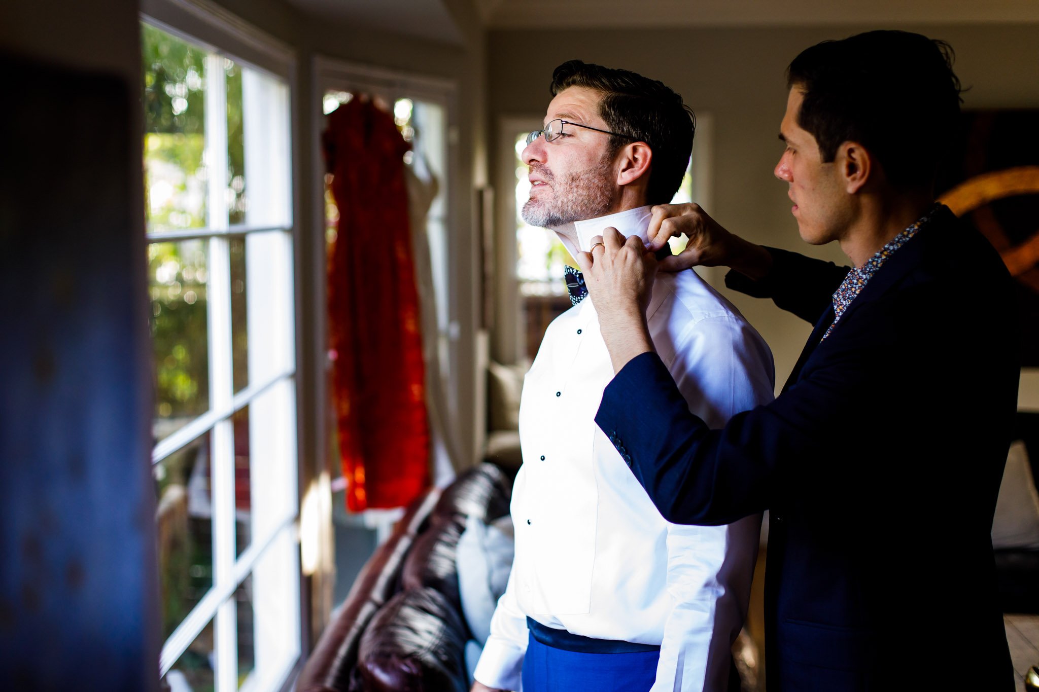 A friend helping the groom adjust his bow tie before the ceremony in Dallas Texas The Amber Studio
