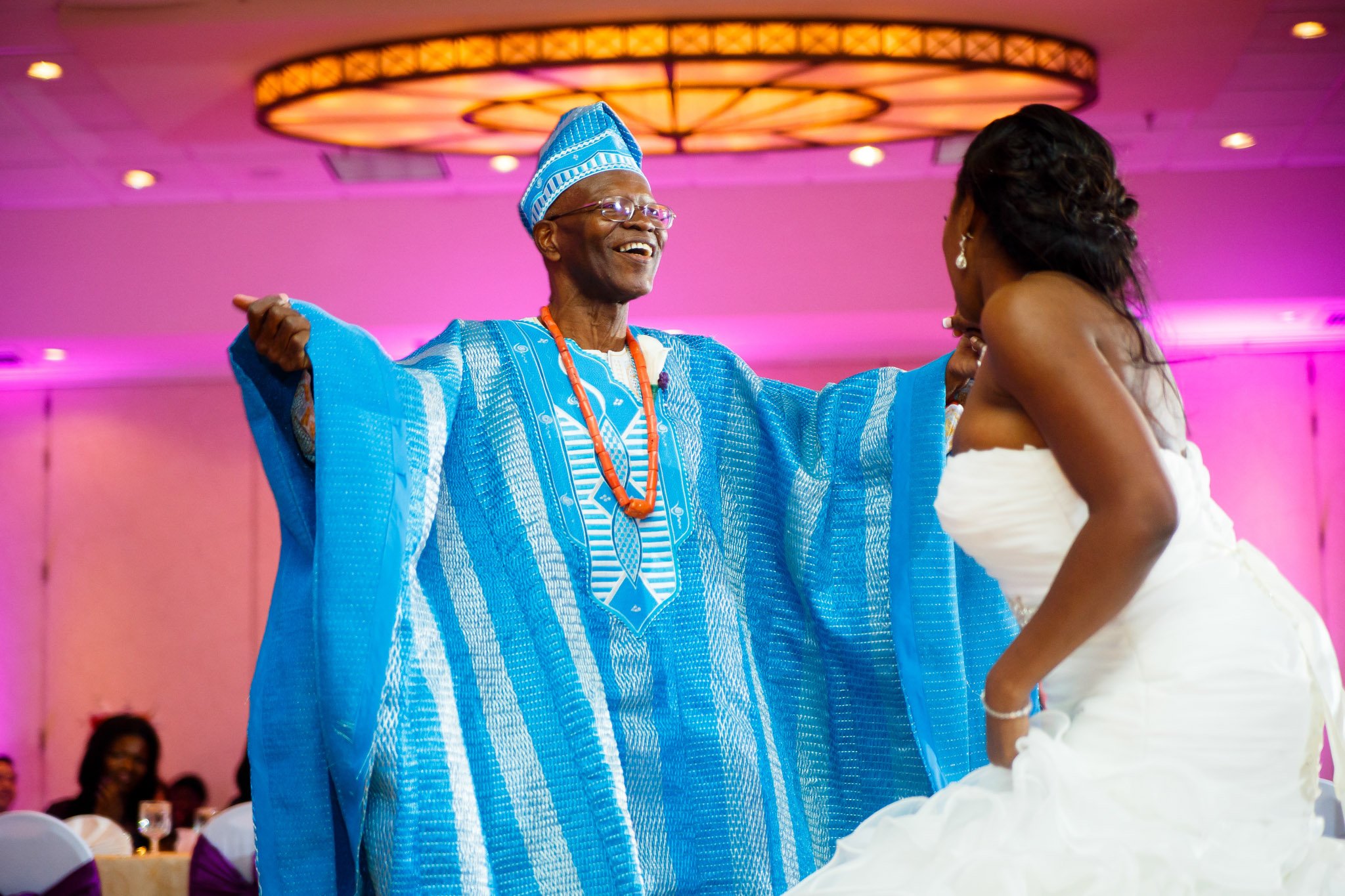 A bride dancing with a man in African formal attire at a Dallas wedding reception The Amber Studio