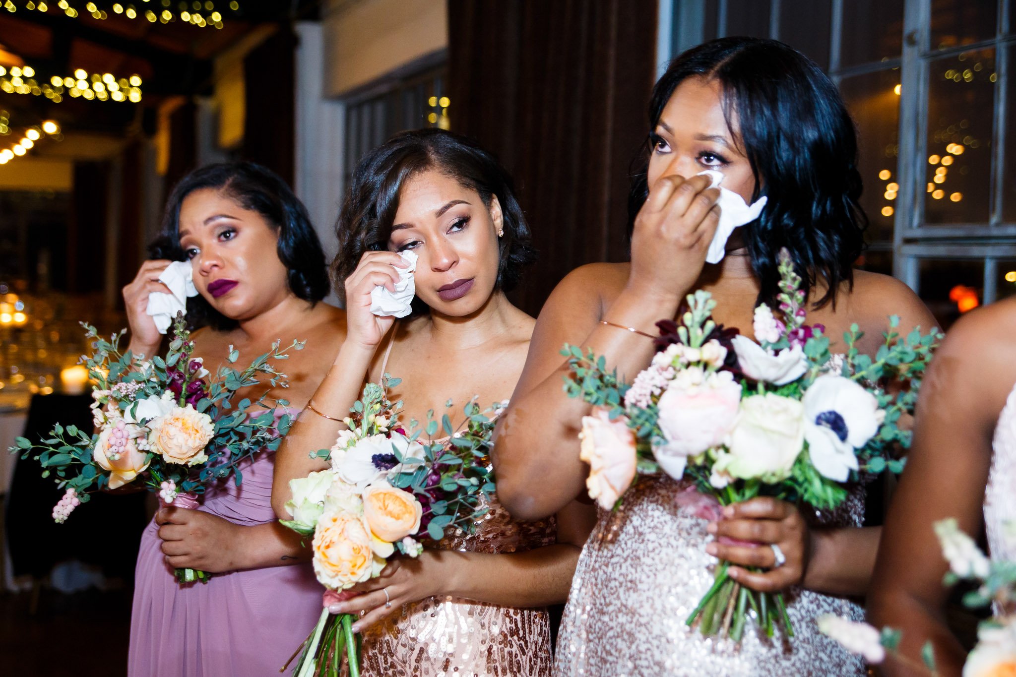 Three bridesmaids all wiping tears away at an emotional wedding ceremony in TX The Amber Studio