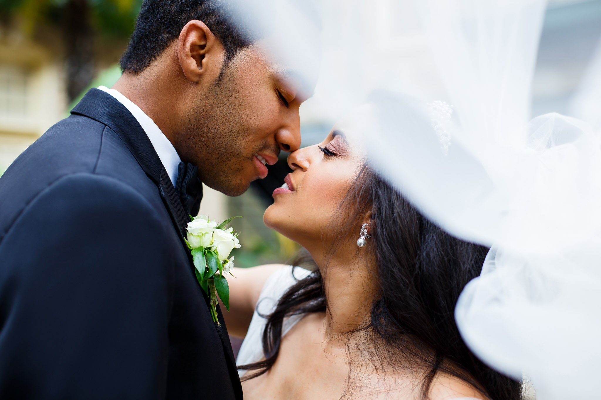 A newlywed couple lean in to kiss under the brides veil in Dallas Fort Worth Texas The Amber Studio