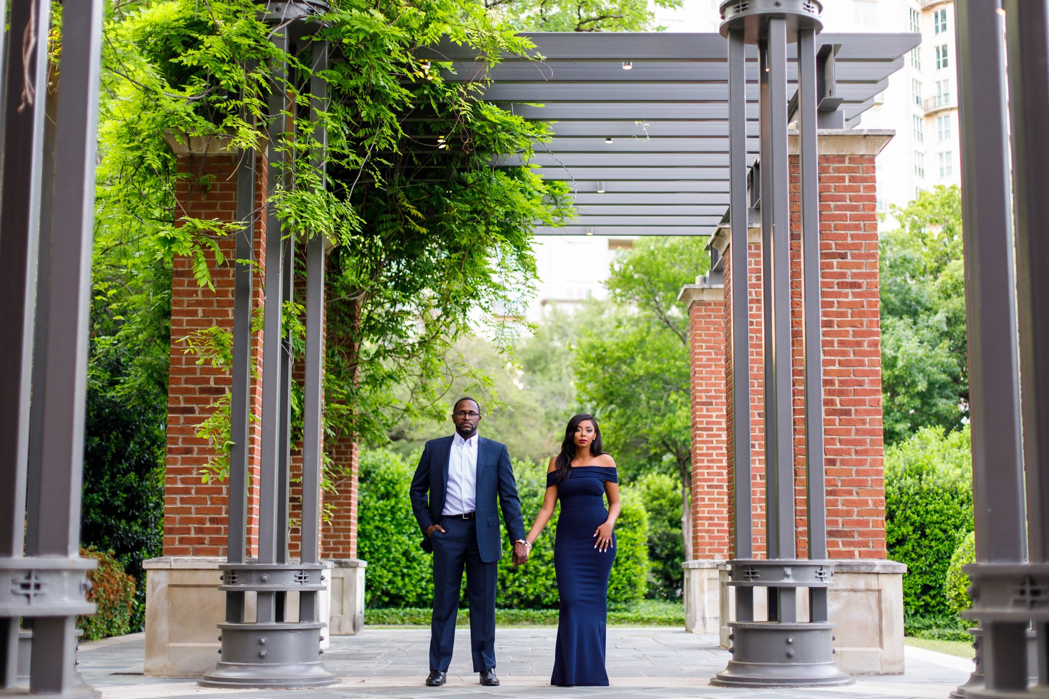 A POC couple wearing formal attired under a metal and brick pavilion in Dallas Texas The Amber Studio