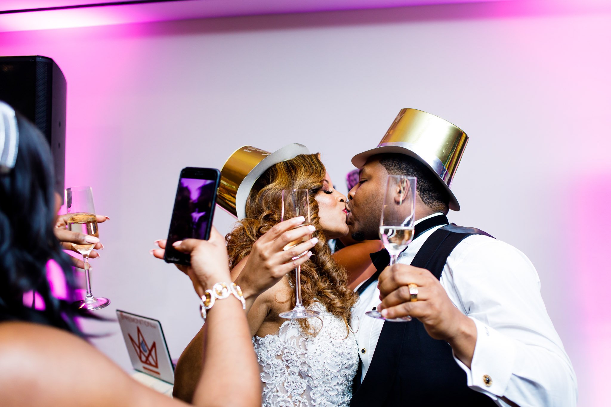 Newlywed mixed race couple kissing and holding up champagne glasses in DFW Texas The Amber Studio