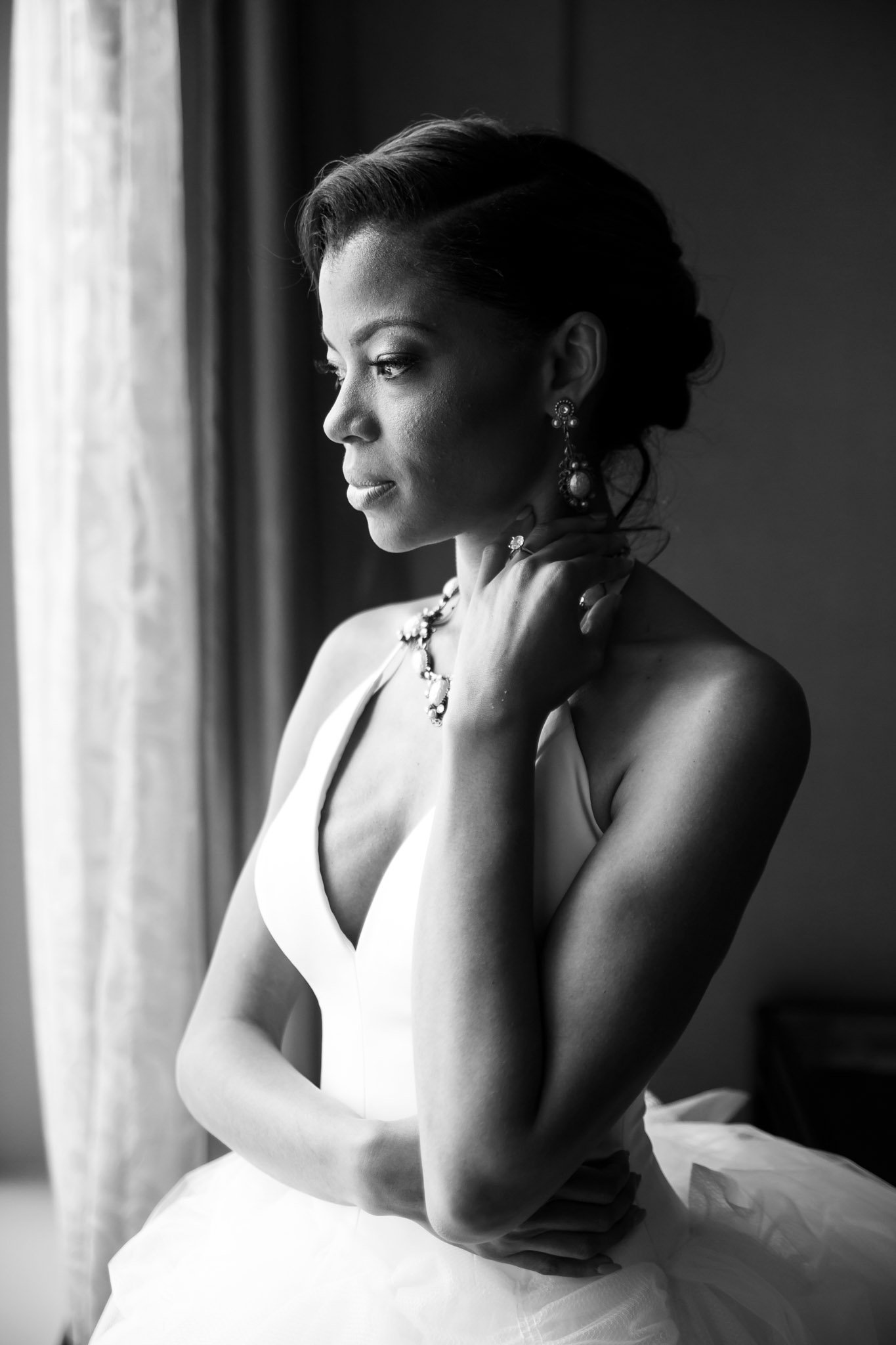 A black bride in a white wedding gown looking out the window in DFW Texas The Amber Studio