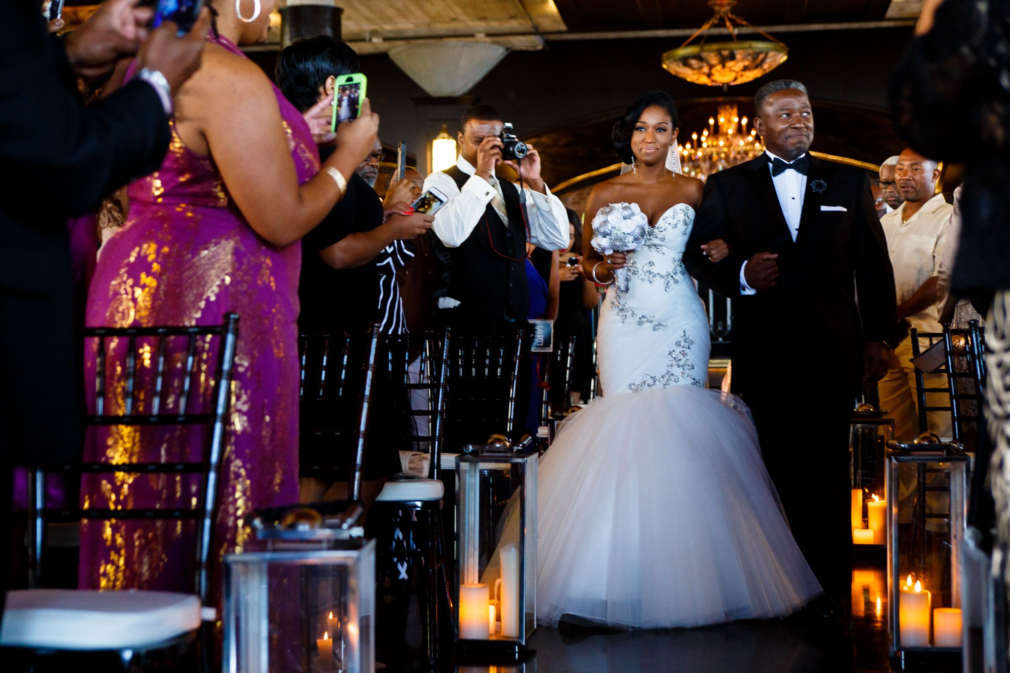 A bride in a strapless gown escorted down the aisle as the guests stand in Dallas Texas The Amber Studio