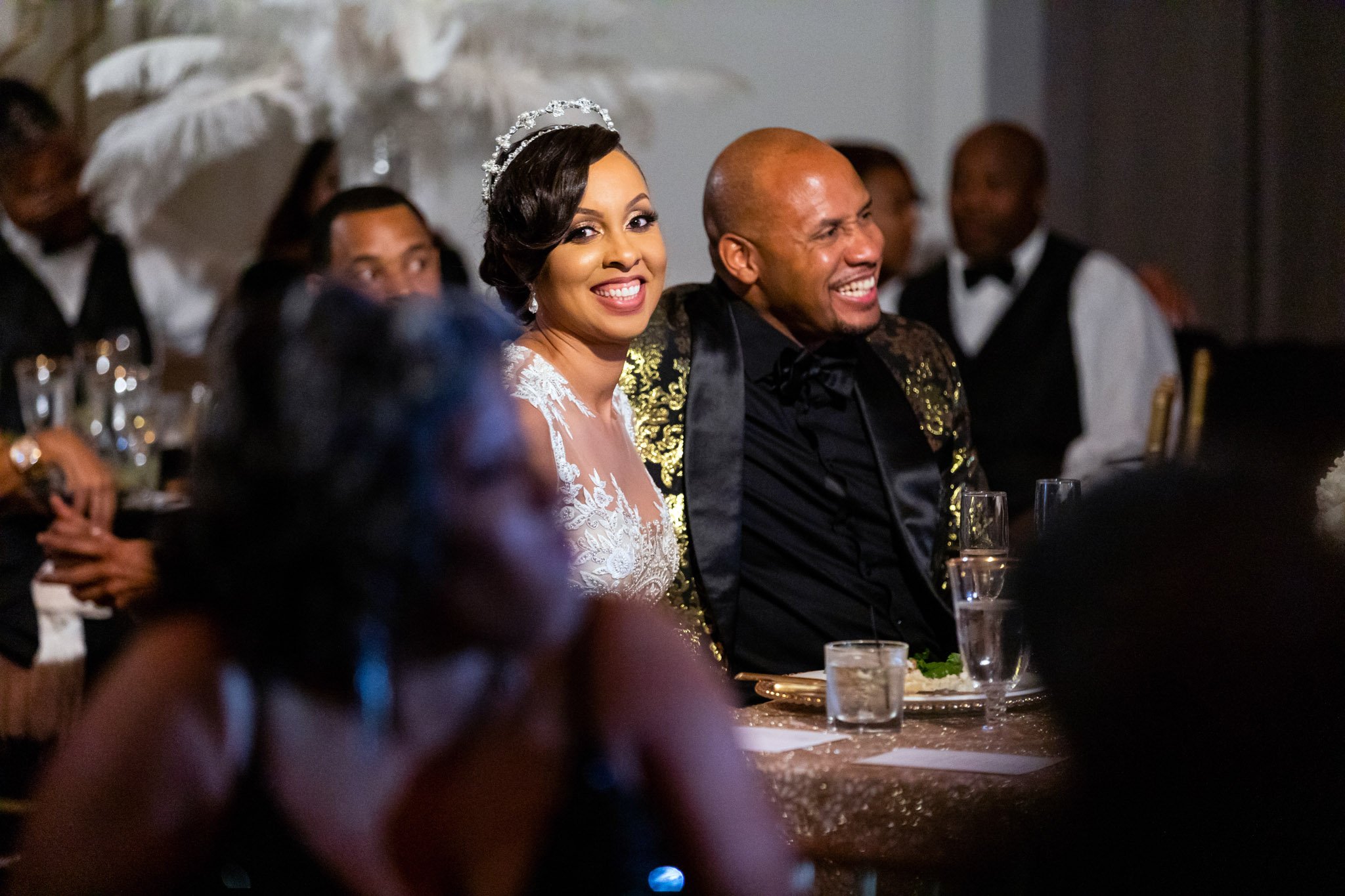 A newlywed couple sitting and smiling at their wedding reception in Dallas Texas The Amber Studio