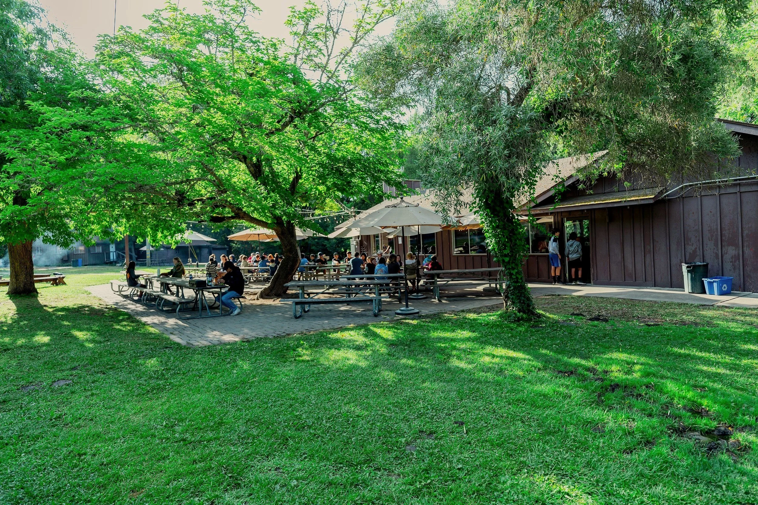 People sitting at the covered outdoor seating next to the Dining Hall.