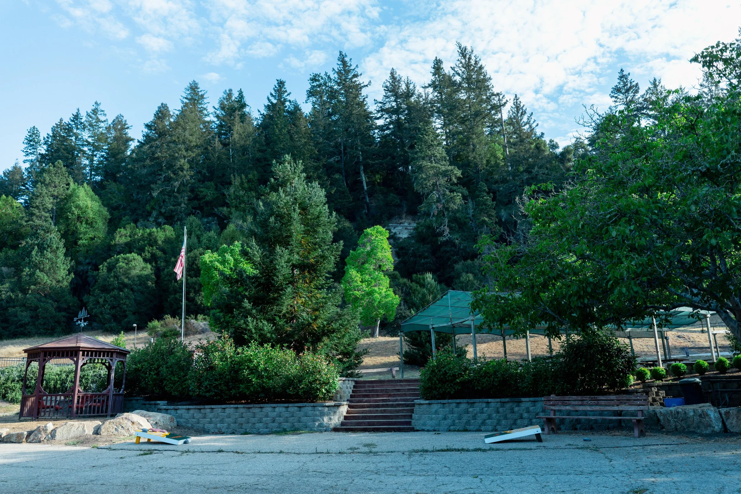 Daybreak Camp's cornhole area with a gazebo and tent covering picnic tables.