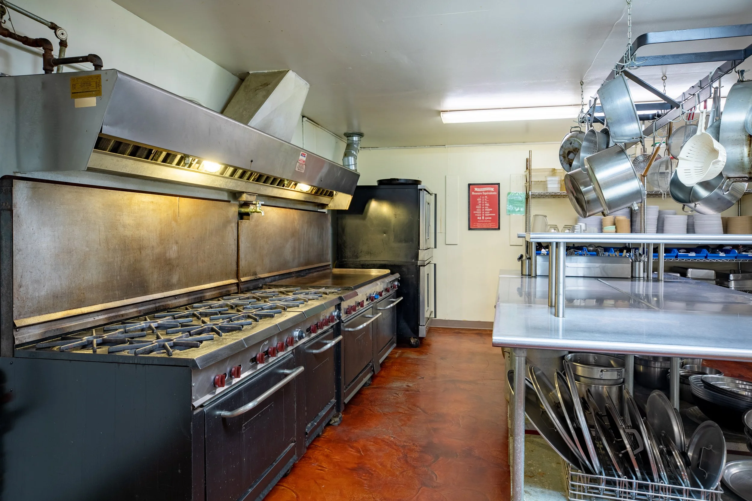 Cooking area of the kitchen, four ovens, two stoves and a large griddle.