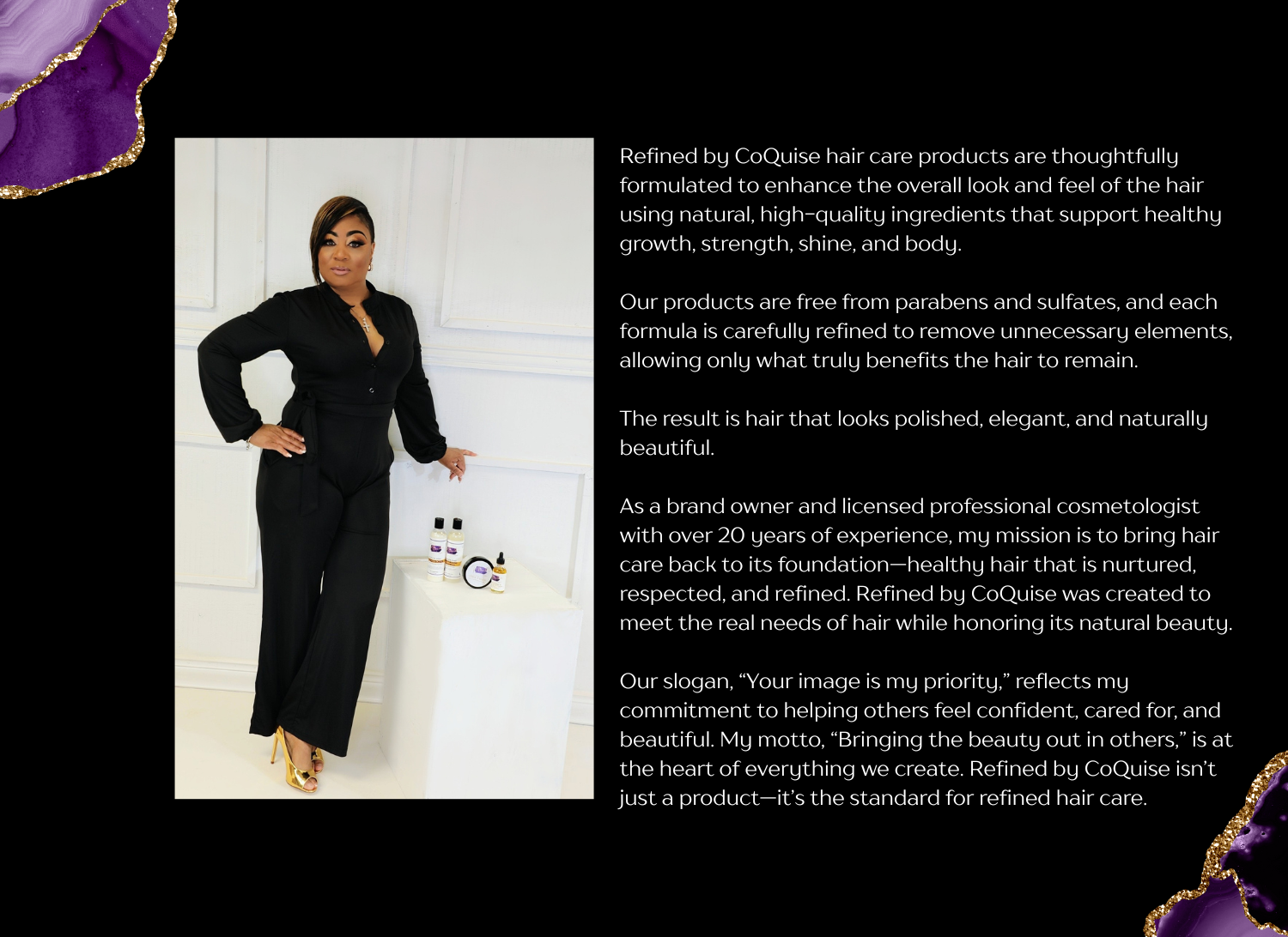 A woman dressed in black standing next to a white table with hair care products, against a white paneled wall.