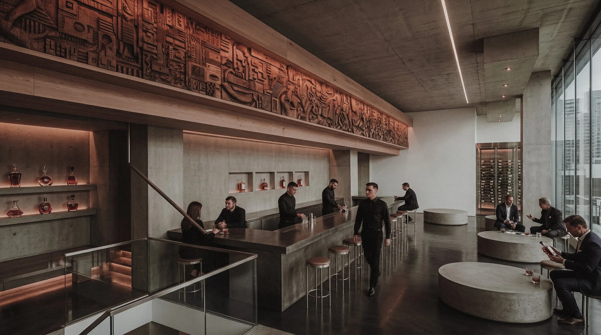 Large-scale hand-carved wood relief by Agata Rek in a brutalist luxury bar. Intricate sculptural panel contrasting concrete architecture and modern minimalist design.