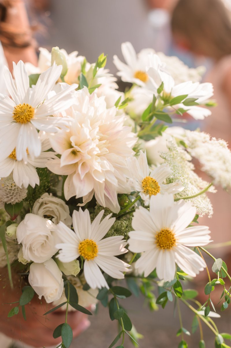 White wedding bouquet featuring daisies and soft blooms photographed in warm golden hour photography light.