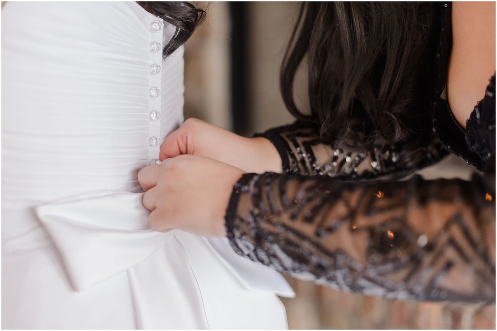 bride getting the dress buttoned by her best friend