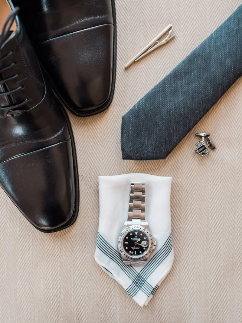  flat lay of grooms shoes, watch, tie and various other accessories 