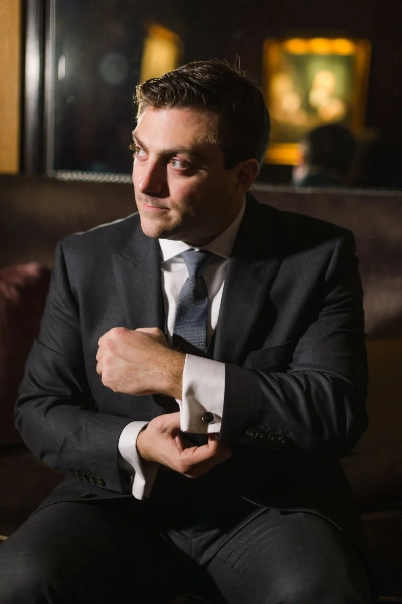  groom sitting down adjusting his cufflinks during getting ready wedding photography 