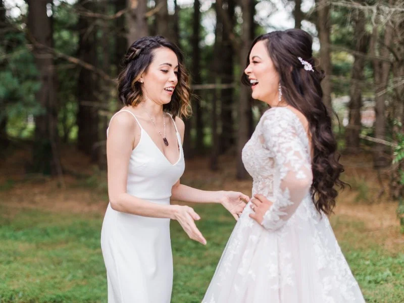  candid photo of a bride and her bridesmaid smiling outside. 