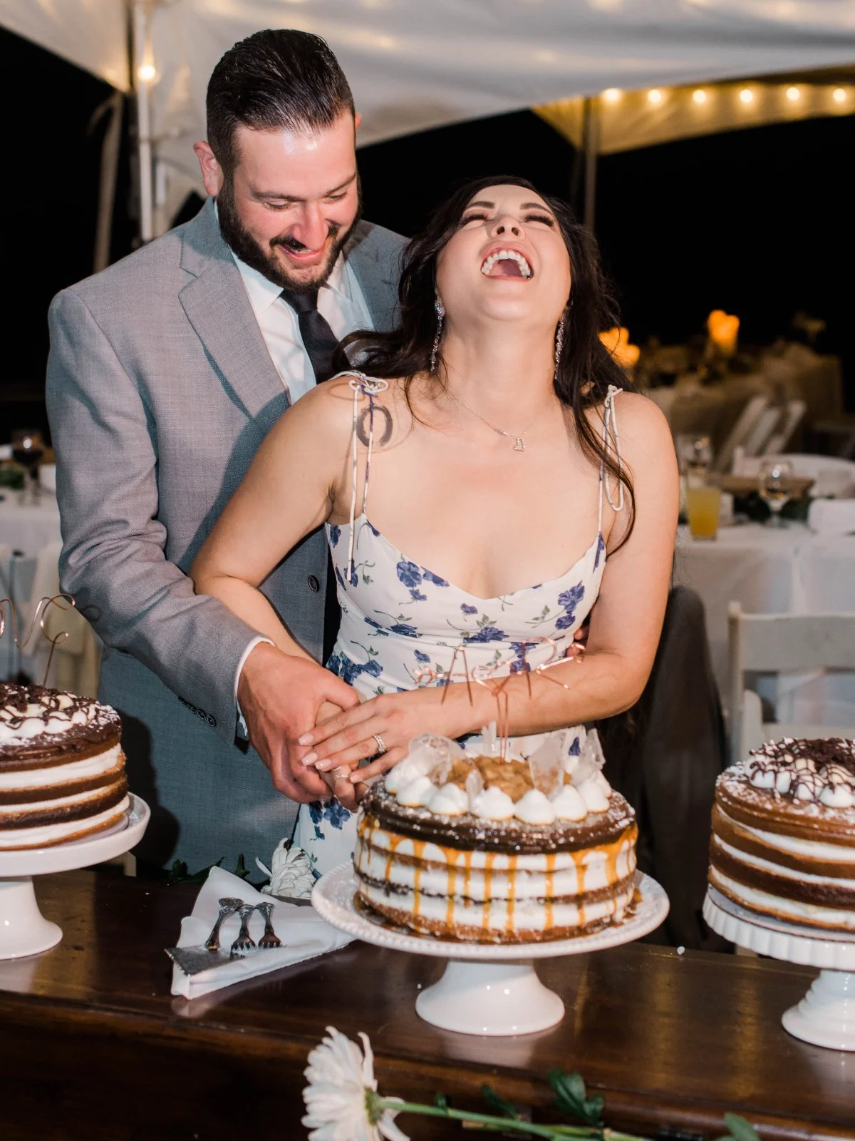  A joyful cake-cutting moment under twinkle lights. Bride wearing her second wedding look. Proof that laughter and dessert go hand in hand at a  luxurious small intimate wedding .   