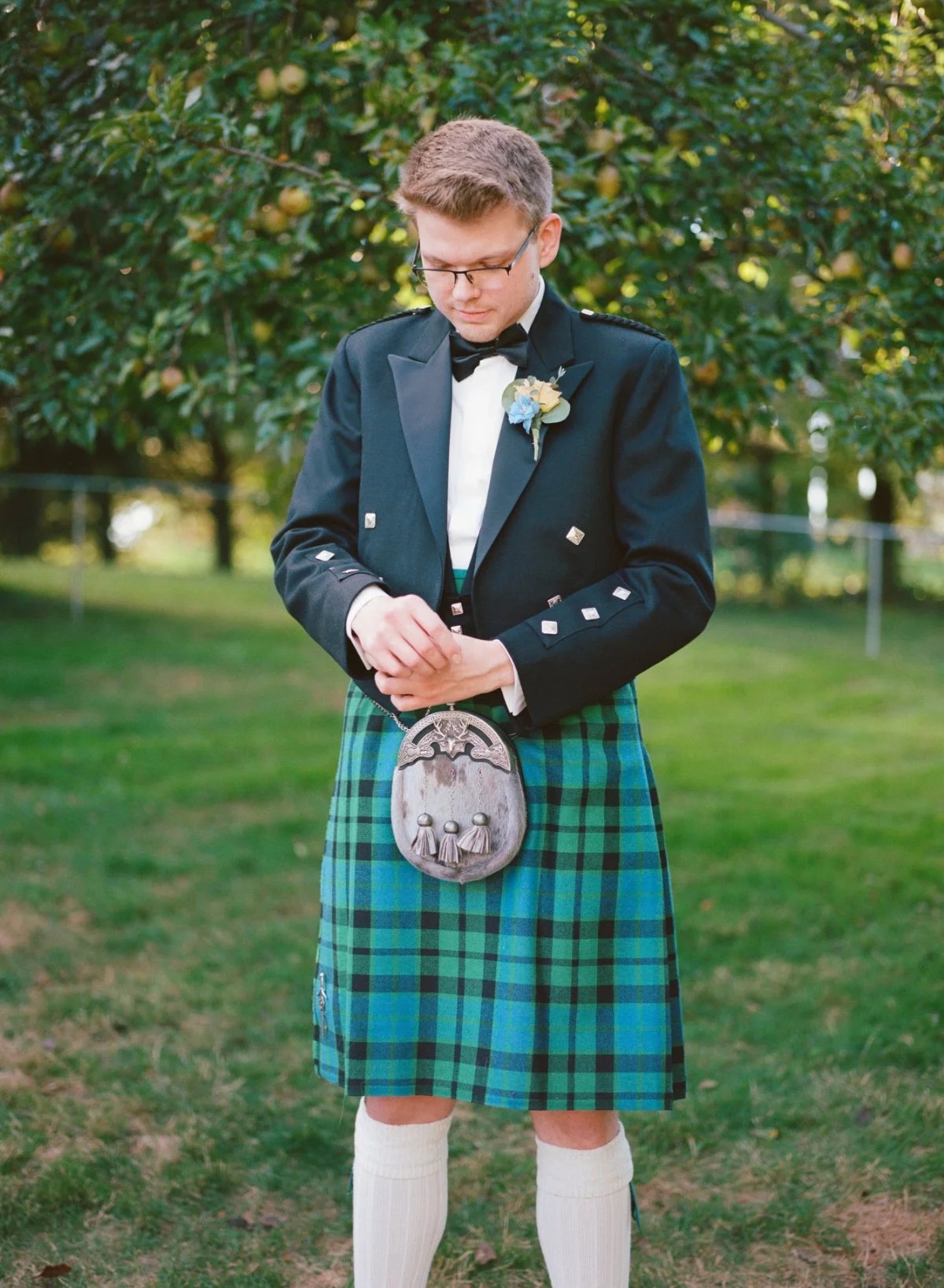  A groom in traditional Scottish attire adjusts his cuff—timeless style with personal meaning, perfect for a heartfelt intimate celebration.   