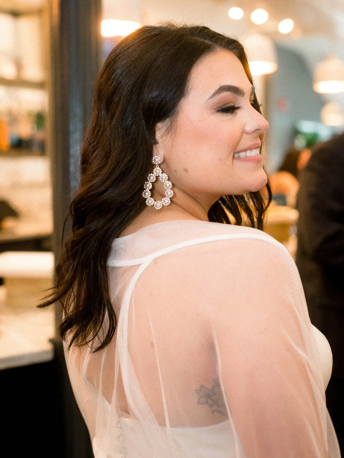  A close-up of a smiling bride with statement earrings and soft glam makeup, glowing with joy at her  luxurious small intimate wedding . 