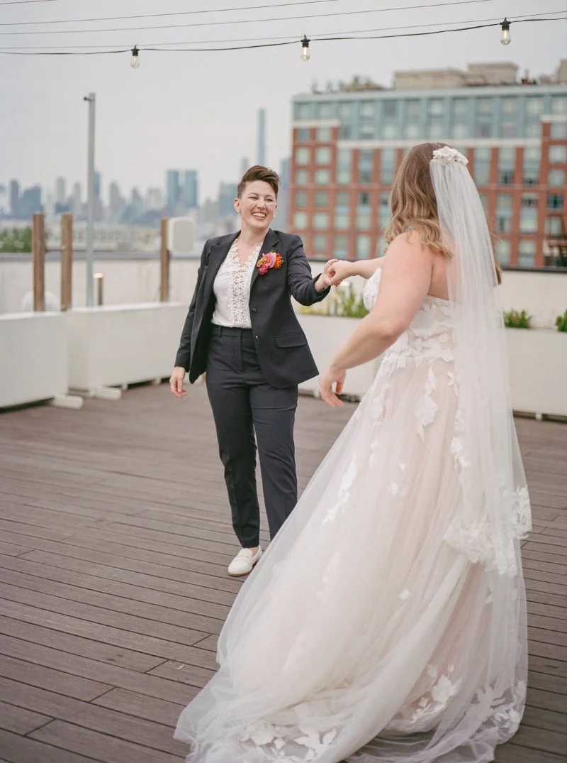 Bride twirls across the rooftop dance floor during a rooftop wedding in Jersey City with the skyline softly blurred behind them. 
