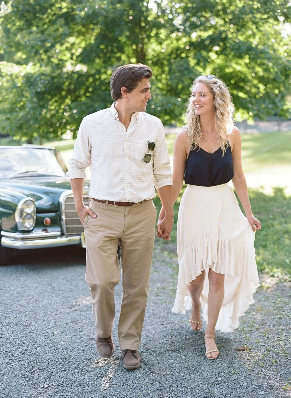  Couple walking outdoors in soft neutral outfits showing relaxed what to wear for engagement photos inspiration. 