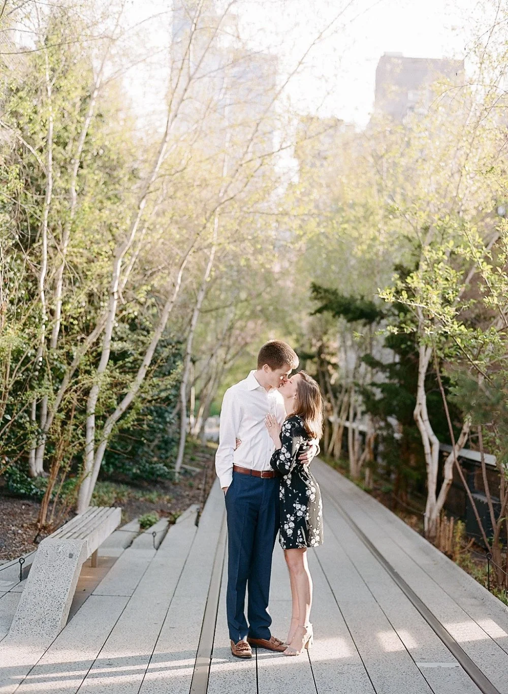  Romantic engagement portrait on a garden pathway surrounded by soft natural greenery. 