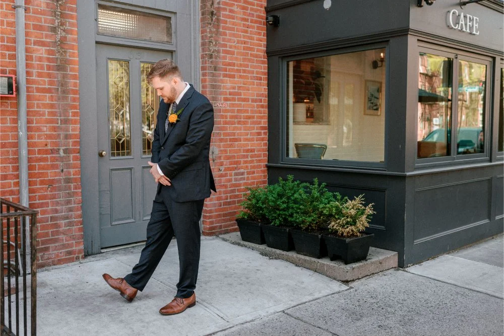  Groom waiting outside a brick building before seeing his bride on their wedding day. 
