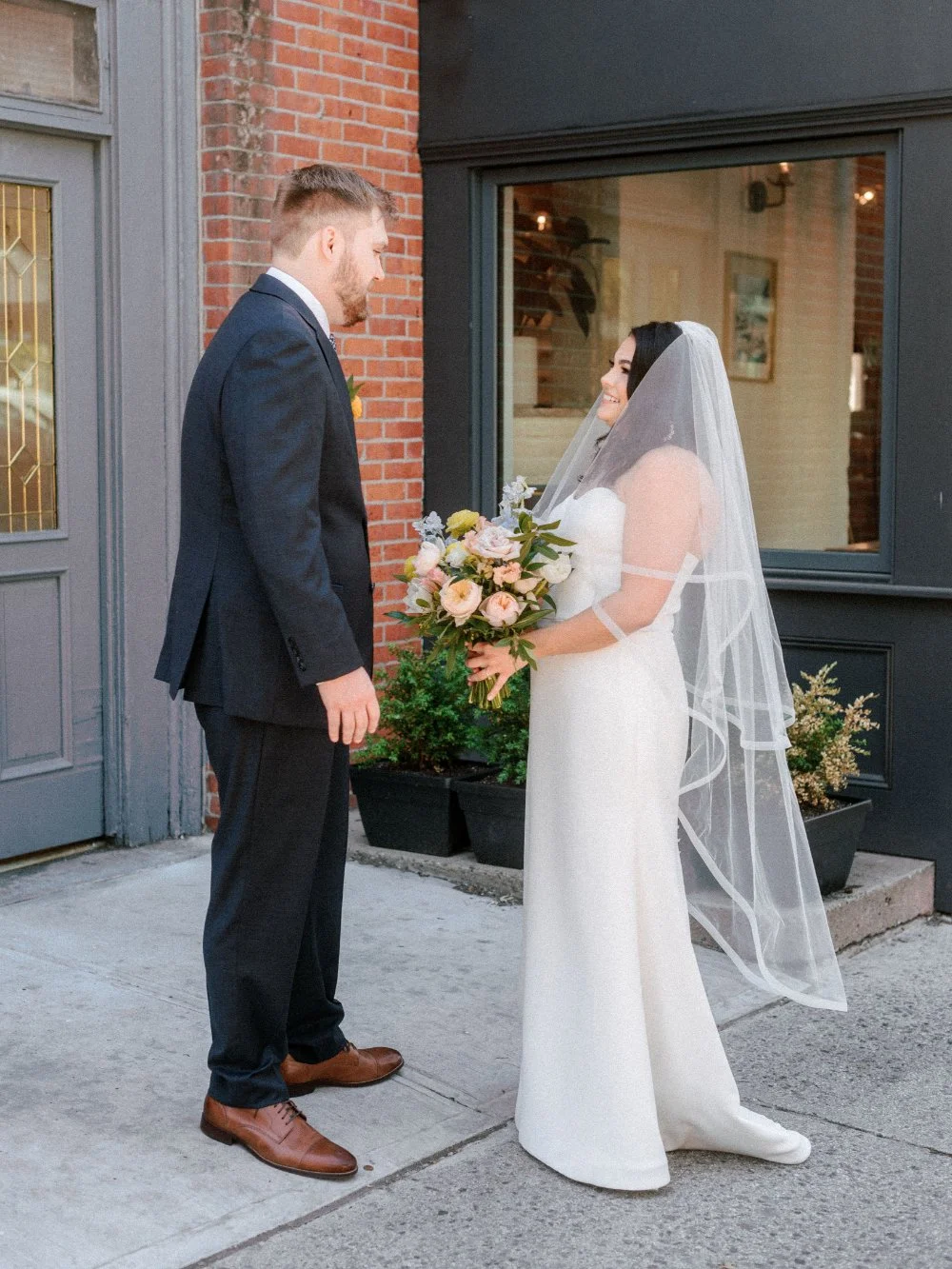  Bride and groom sharing a heartfelt moment together outside their wedding venue. 