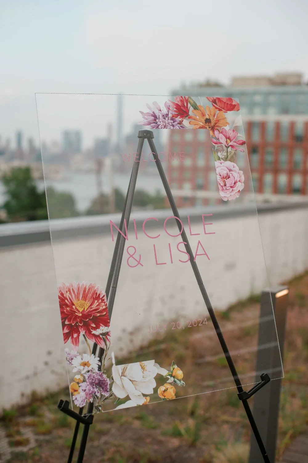  LGBTQ wedding photographer captures modern wedding welcome sign with colorful floral details on a rooftop. 
