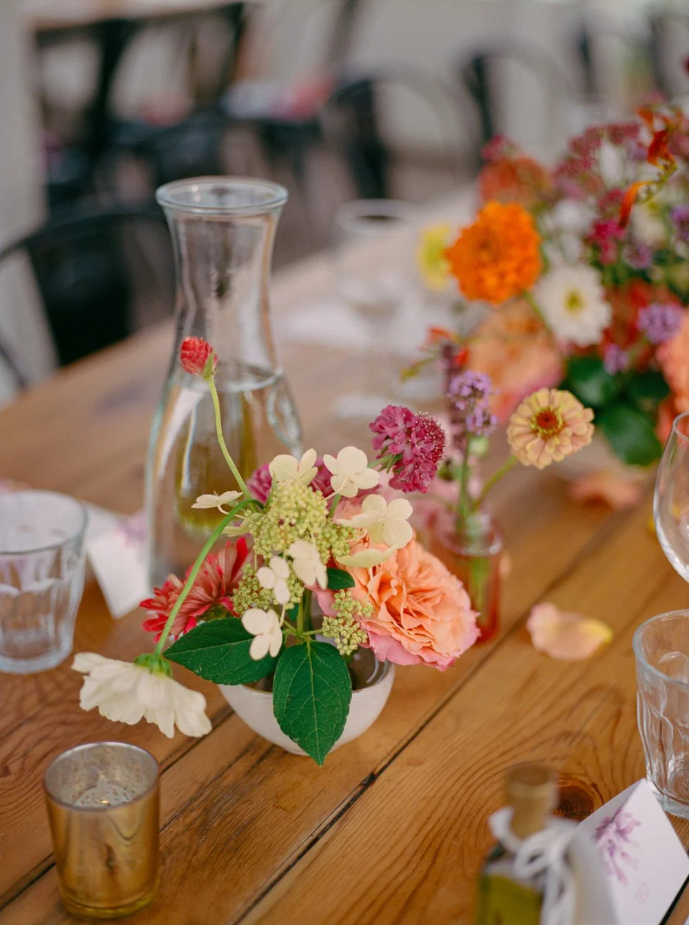  LGBTQ wedding photographer captures colorful floral centerpieces displayed on rustic wooden reception tables. 