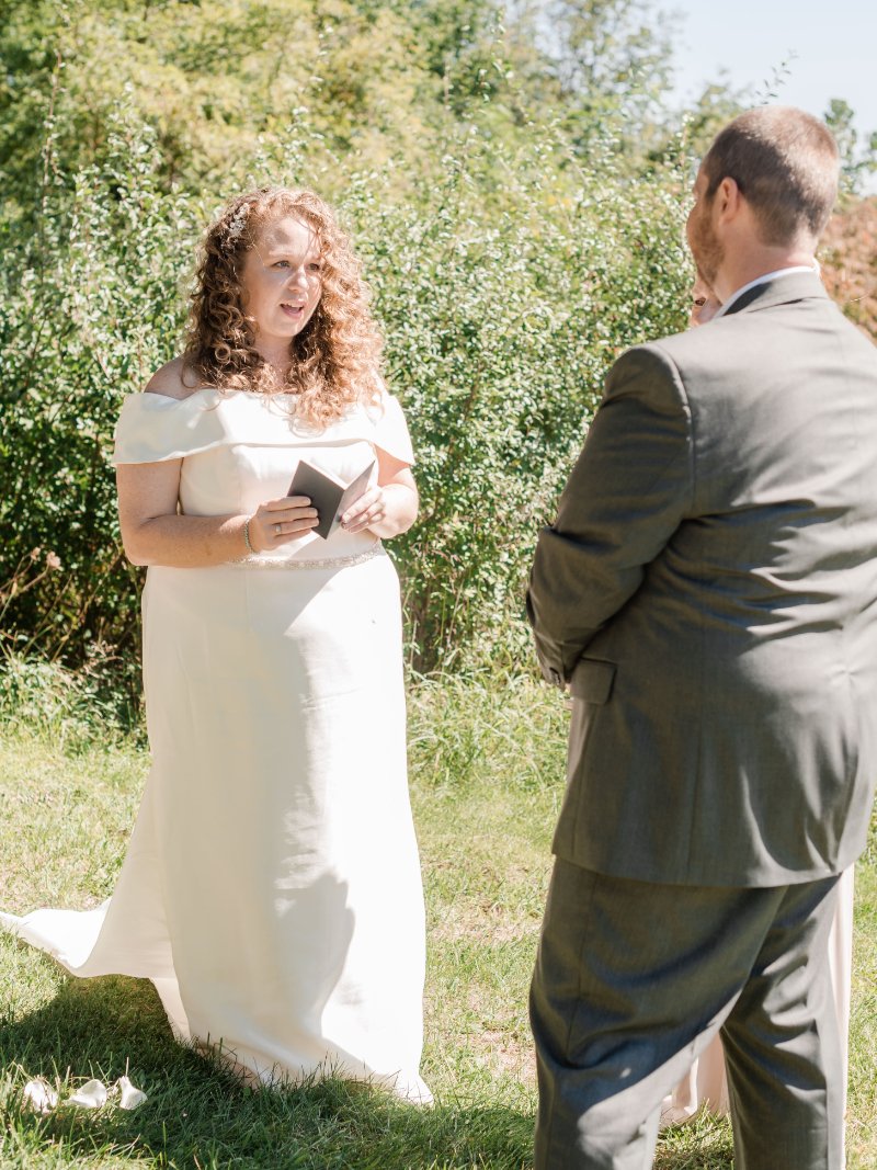   Bride reading her handwritten vows during an intimate outdoor wedding ceremony.  