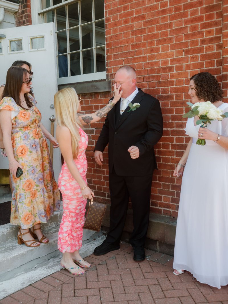  Wedding photography checklist moment capturing the couple laughing with friends outside their intimate wedding venue. 