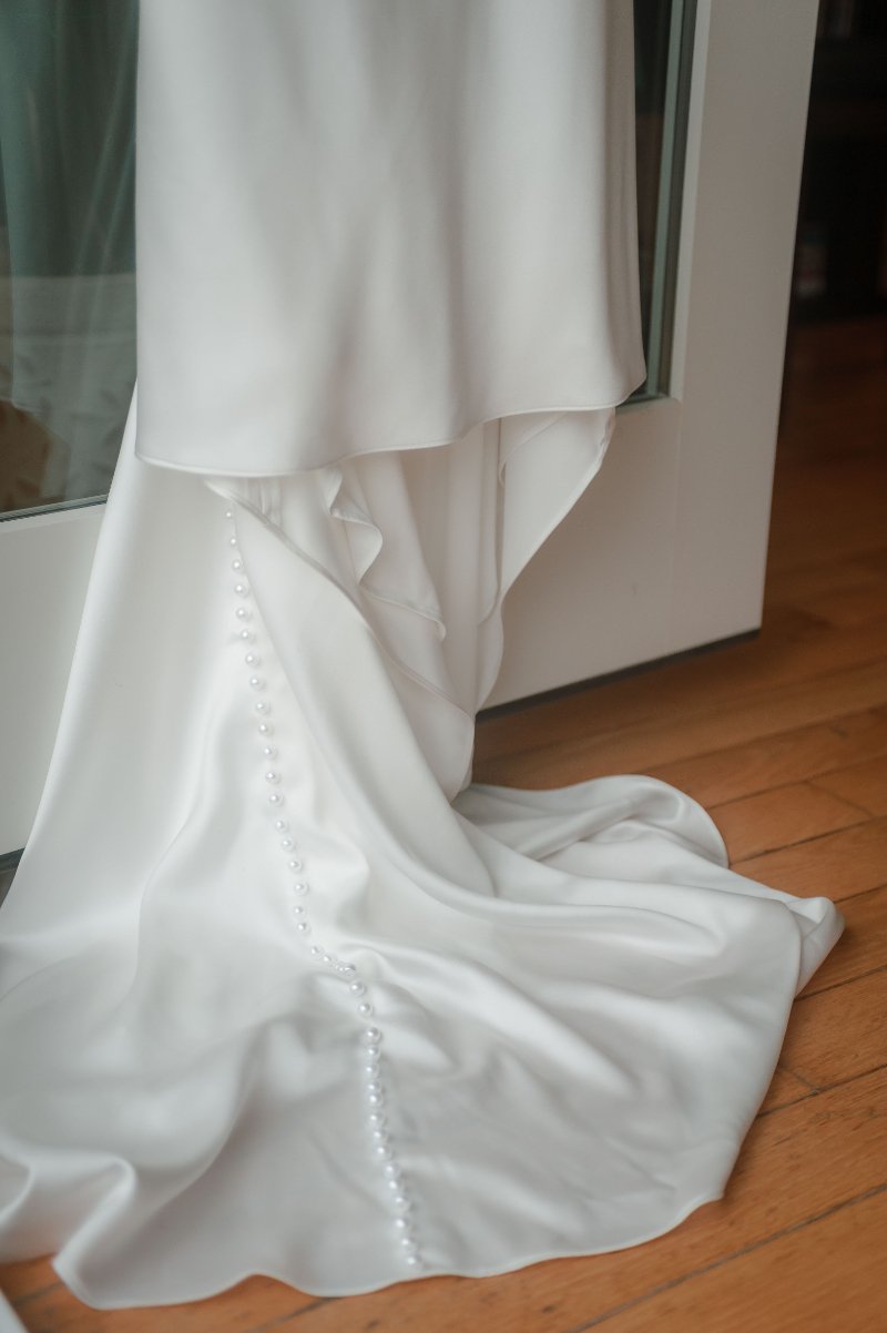  Close-up of a white wedding dress train with delicate buttons, highlighting timeless wedding dress tips. 