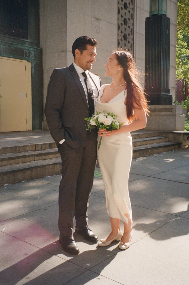 Couple smiling at each other outside courthouse after ceremony before they announce your elopement.