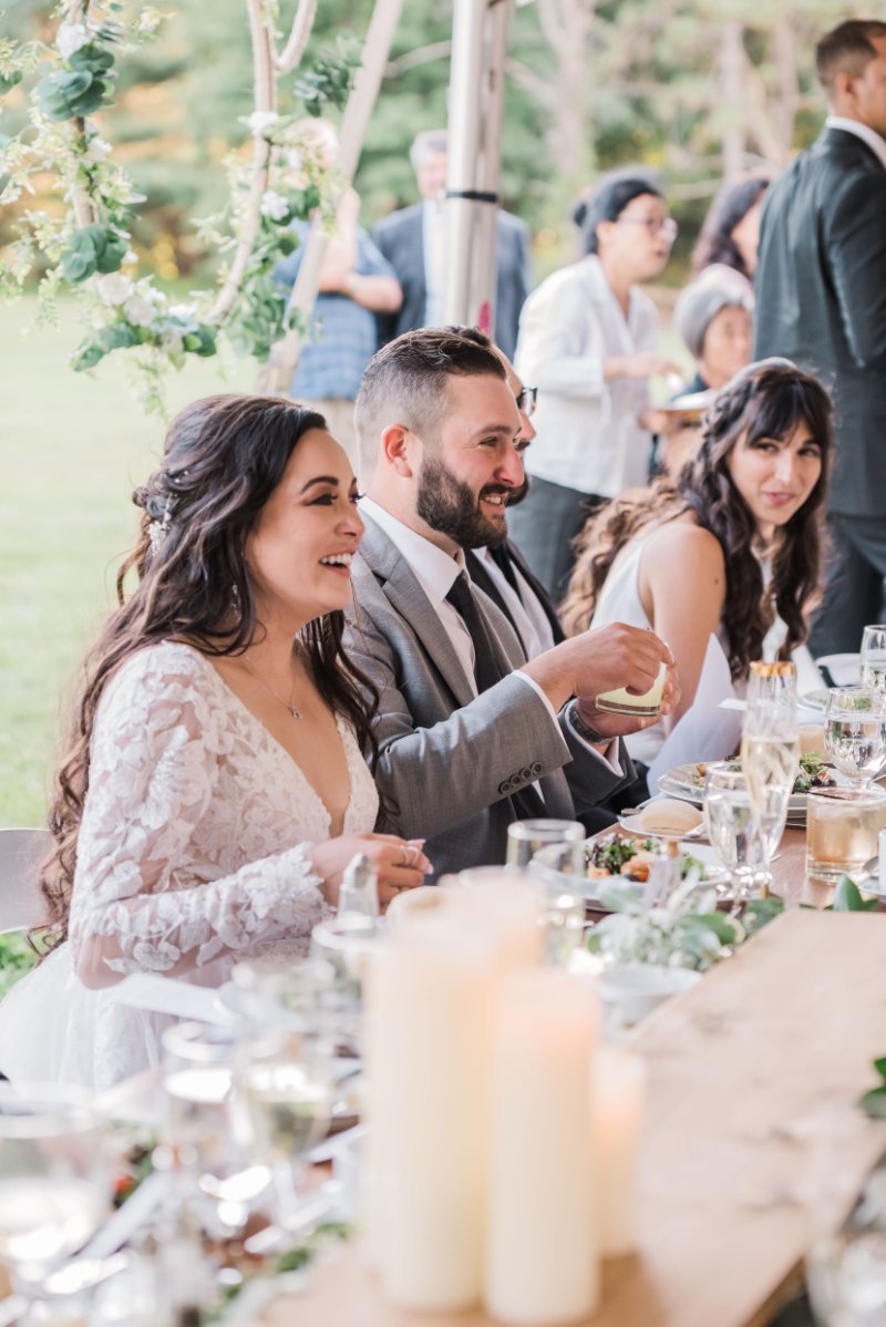 Couple at intimate wedding dinner table sharing meal and laughter to celebrate with family together