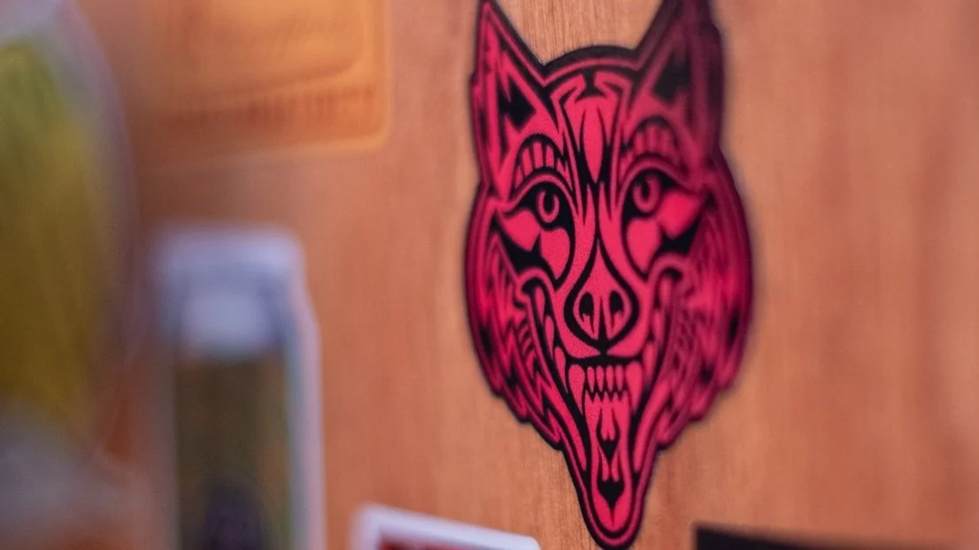 A Howling Wolf Taqueria wolf's head logo sticker on a wall