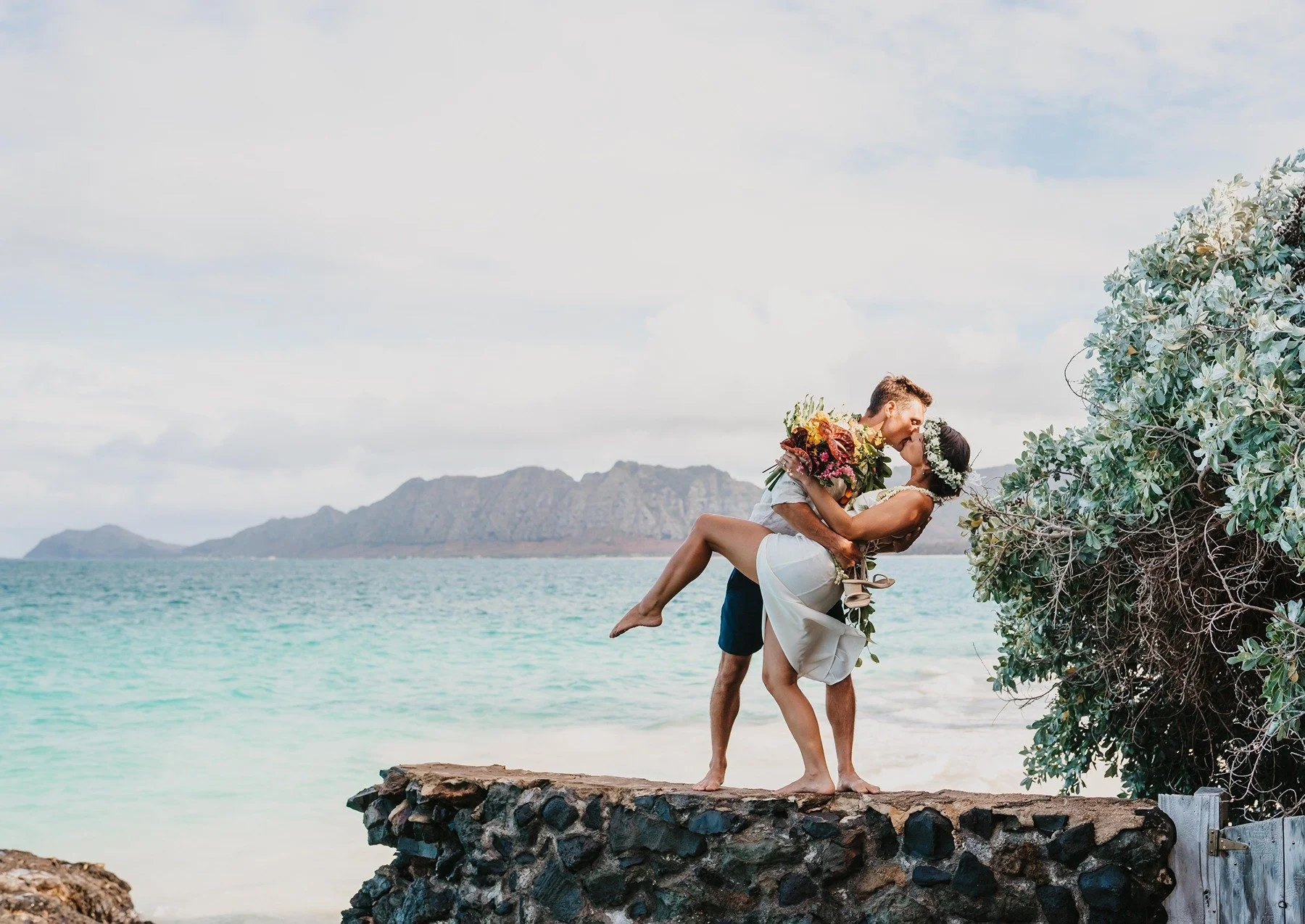 Newlyweds kiss on the beach in Hawaii