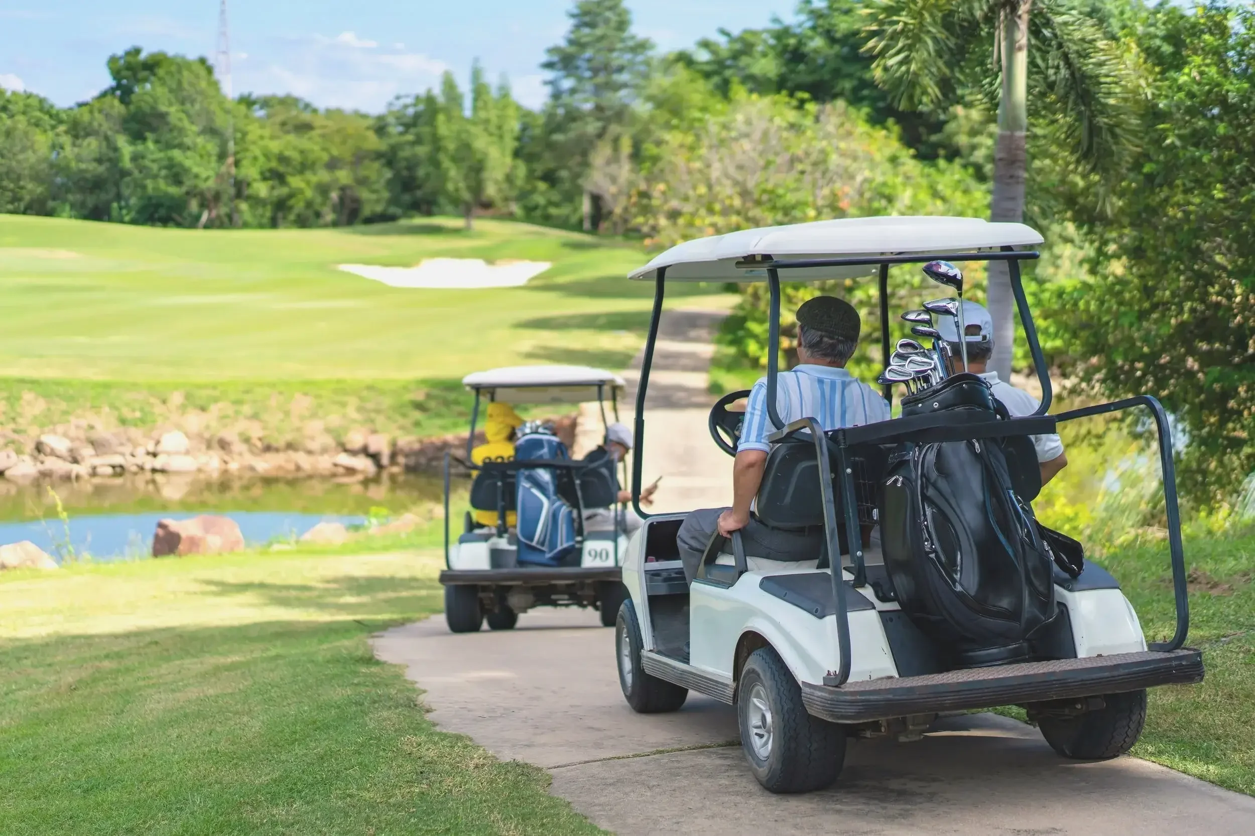 Golf carts on cart path driving towards green