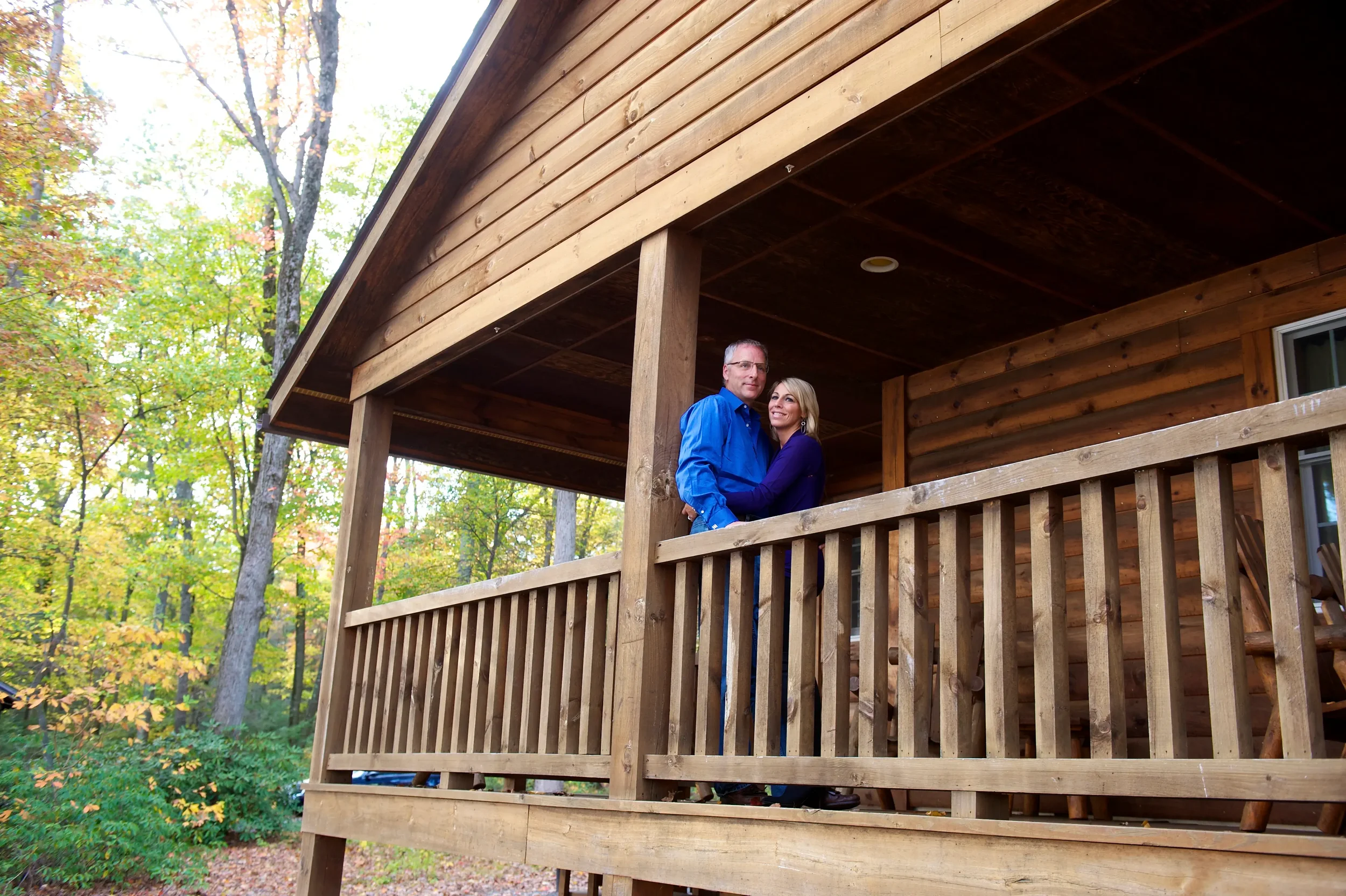 Couple relaxing on the porch of a wooded Pocono cabin at Mountain Springs Lake Resort