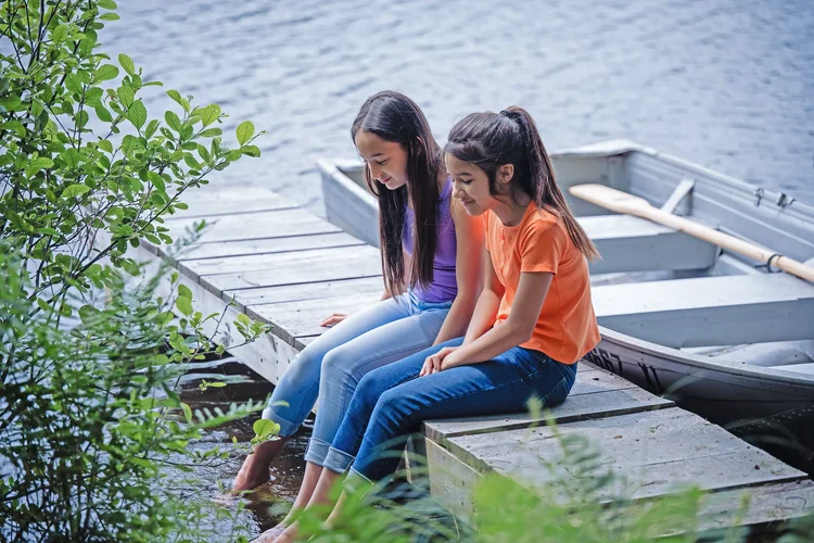 Children sitting together on a wooden dock beside the private lake