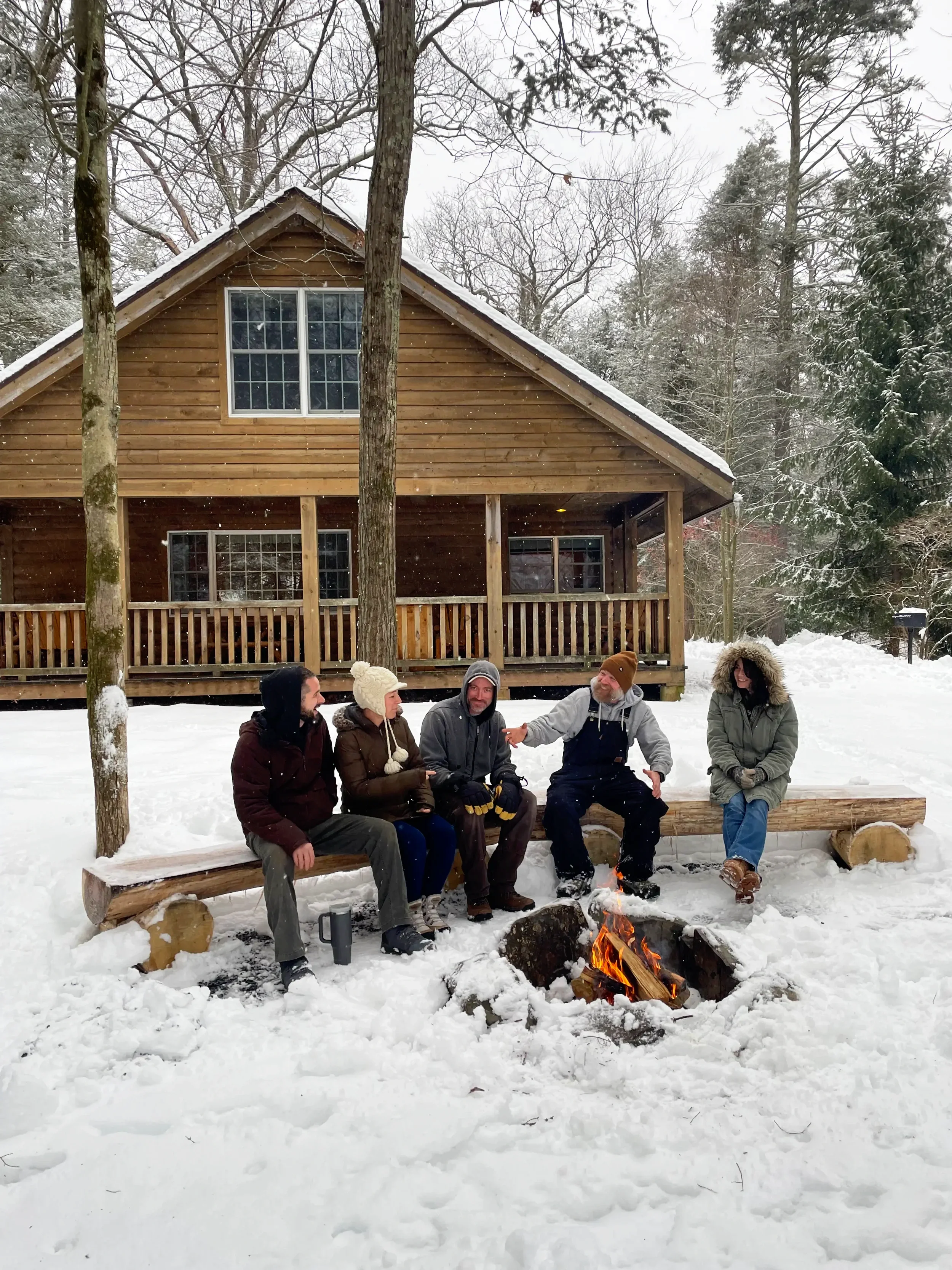 Guests relaxing around a winter firepit outside a Pocono cabin at Mountain Springs Lake Resort
