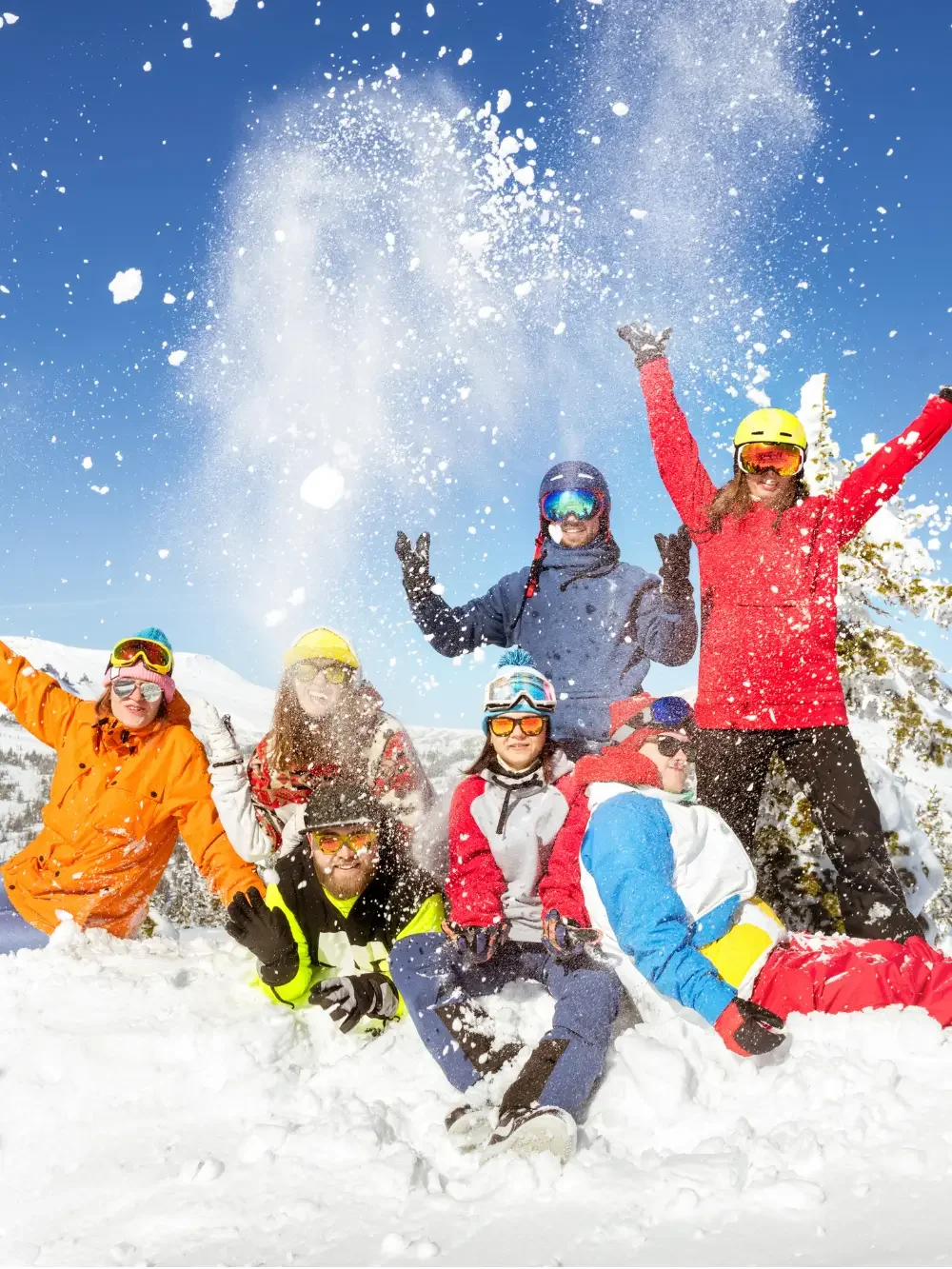 Group of skiers in colorful winter gear celebrating in fresh snow on a sunny mountain slope near Mountain Springs Lake Resort