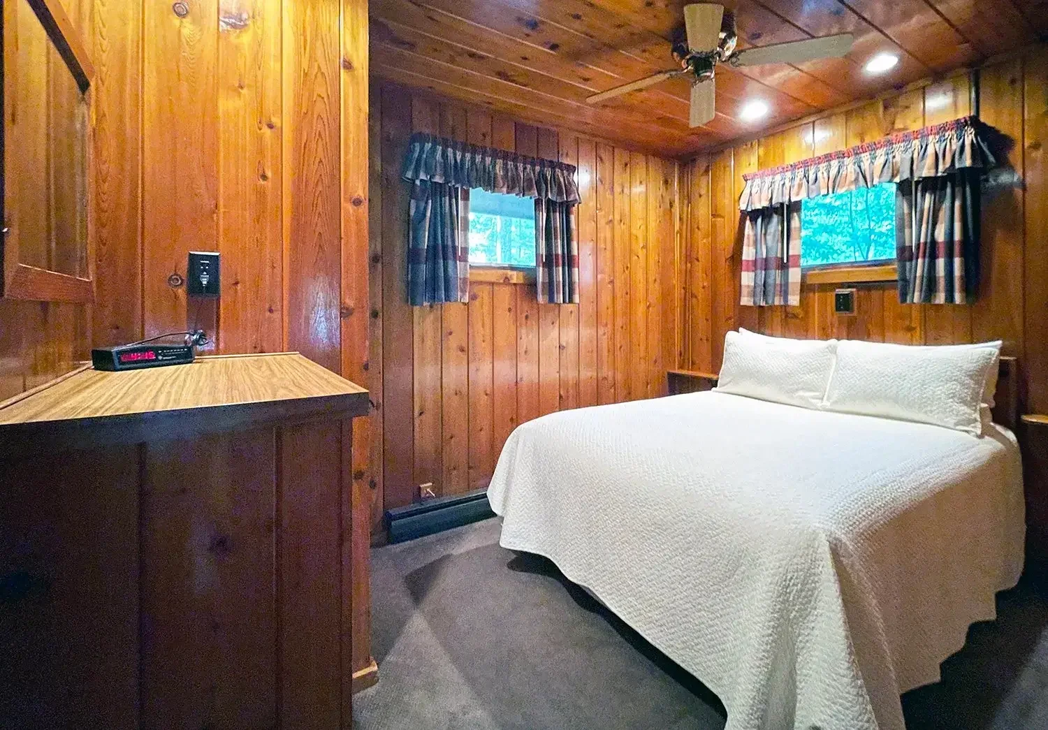 Bedroom with two twin beds, knotty pine walls, and ceiling fan — ideal for guests or children.