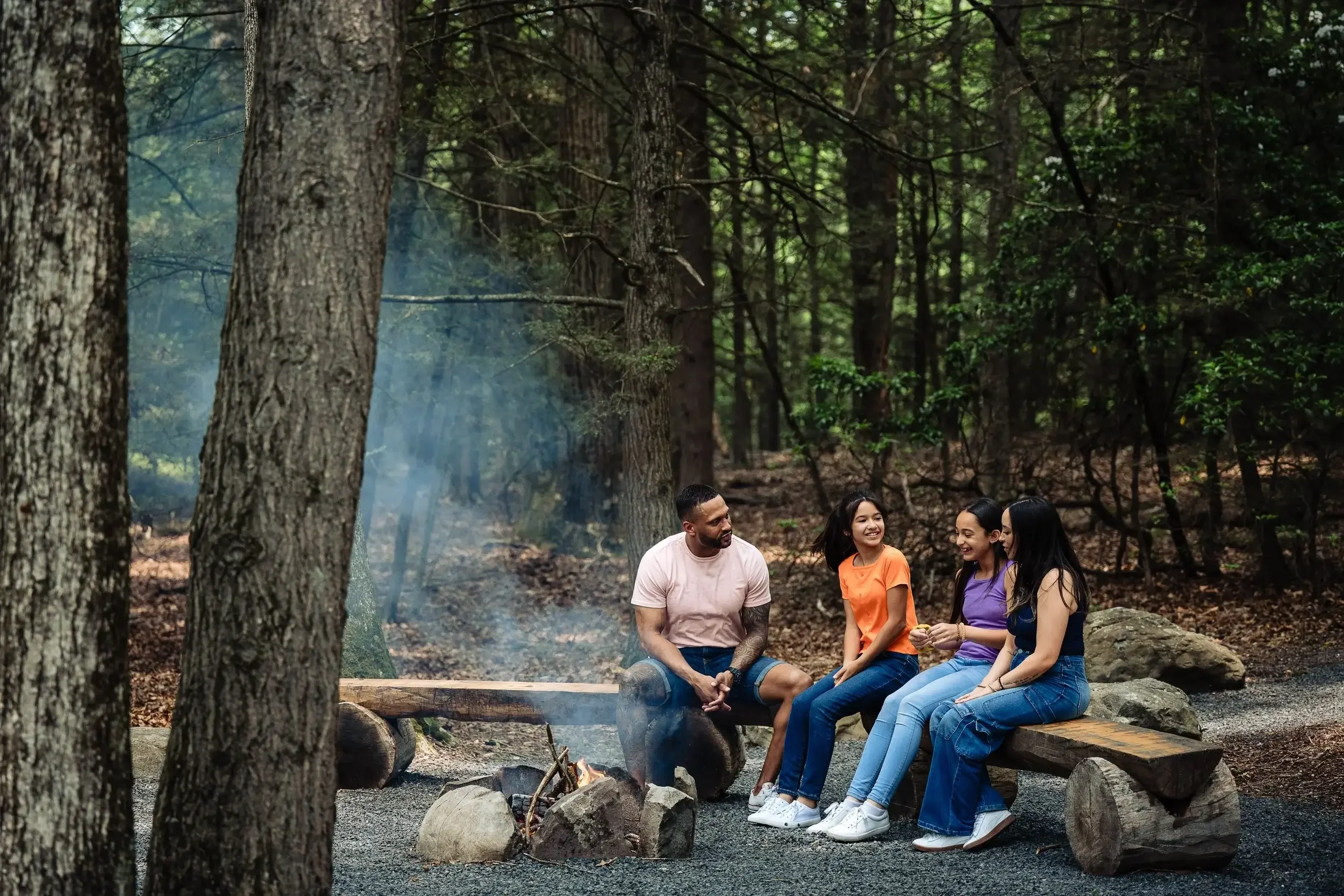 Family sitting around a wooded fire pit at Mountain Springs Lake Resort