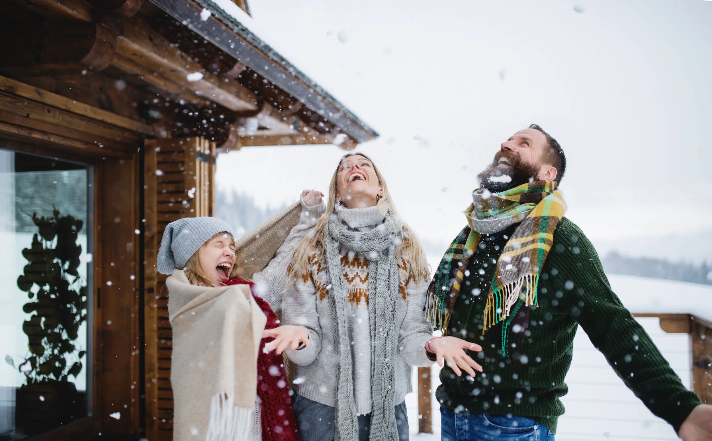 Family enjoying snowfall outside a cozy Pocono cabin getaway