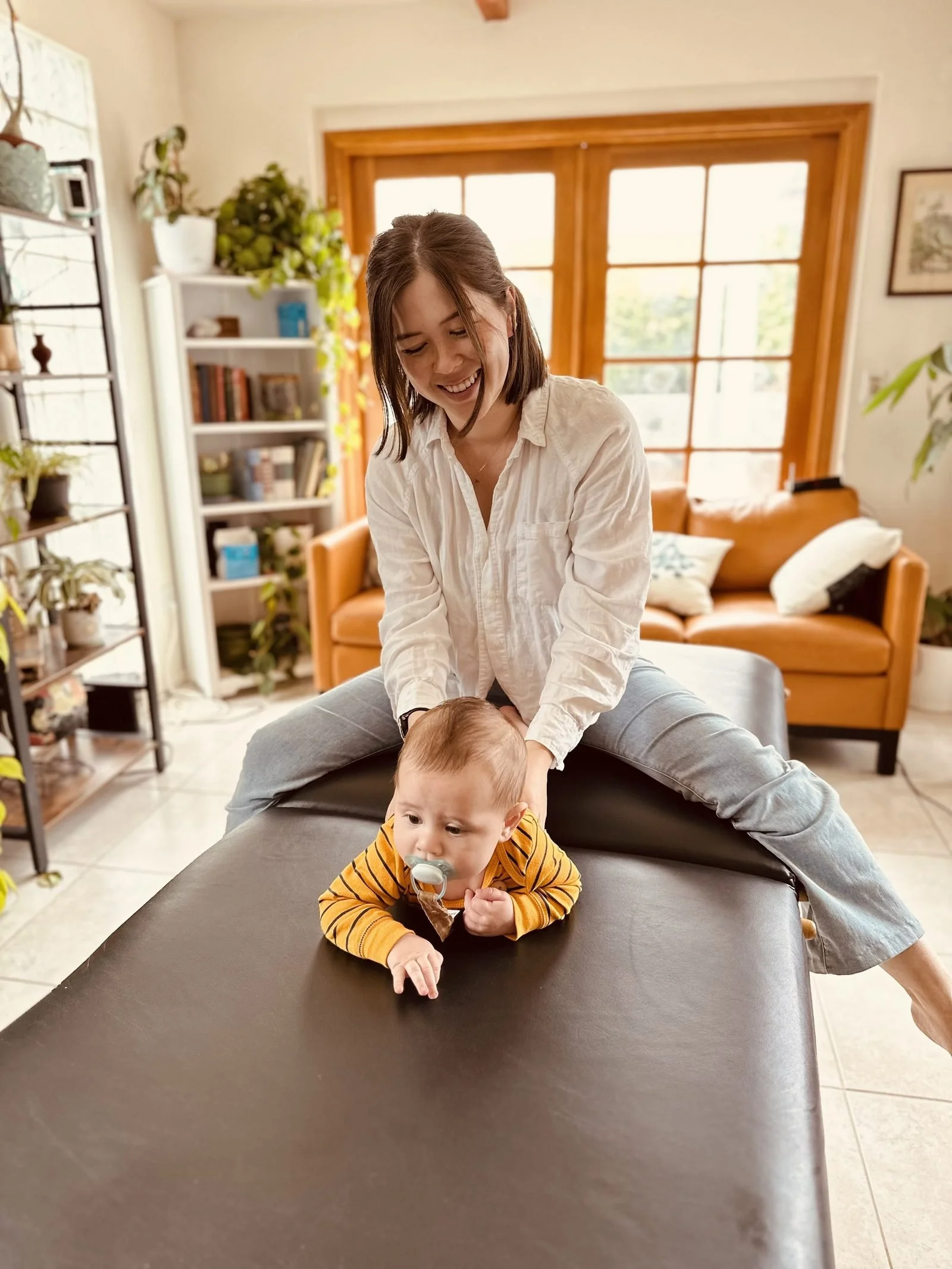 A chiropractor gently working with an infant on a treatment table.