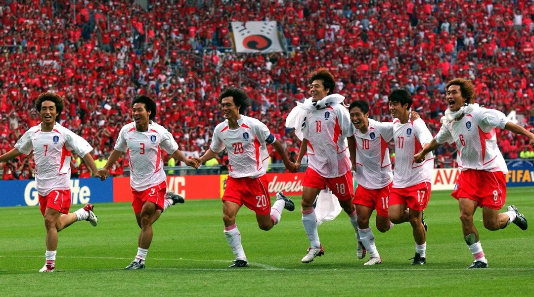 Players on South Korean's national team run arm in arm, emblematic of the unity of the Global Asia tournament hosted by Japan and South Korea in 2002,